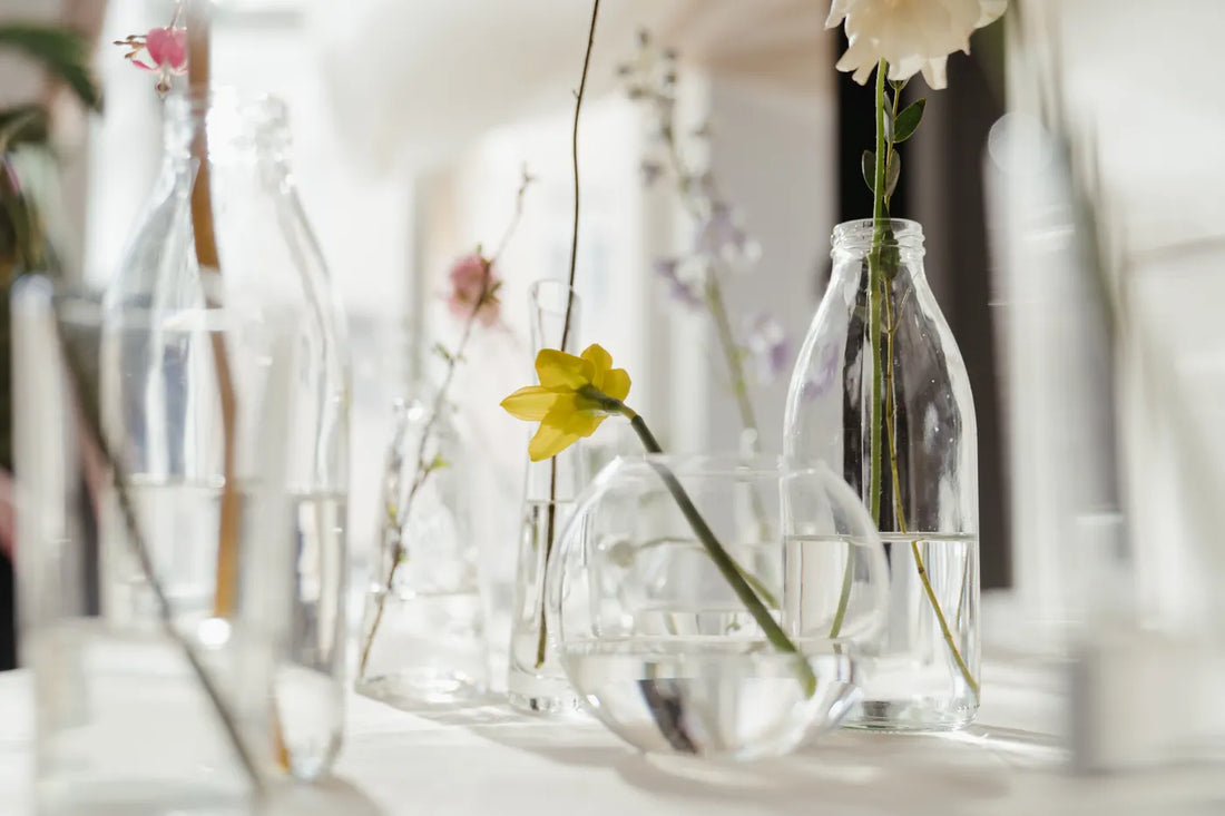 Fleurs légères disposées dans plusieurs vases en verre transparent — photographie d’inspiration, hors catalogue Taahys.